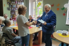 na zdjęciu - suczestnicy spotkania - Seniorzy, Dyrektor OPS Mieroszów oraz Burmistrz Mieroszowa wręczający opaski