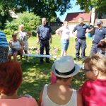 na zdjęciu widoczni seniorzy oraz policjanci siedzący i rozmawiający w ogródku