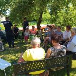 na zdjęciu widoczni seniorzy oraz policjanci siedzący i rozmawiający w ogródku