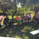 na zdjęciu widoczni seniorzy oraz policjanci siedzący i rozmawiający w ogródku
